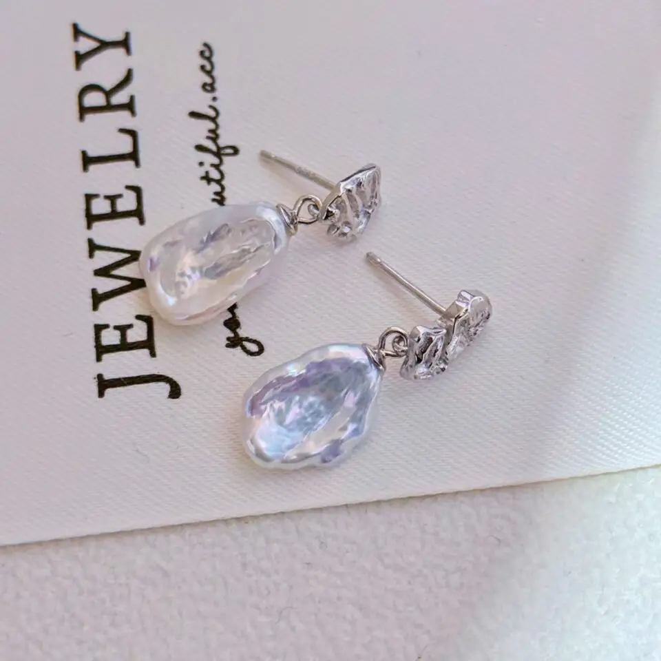 Ces boucles d'oreilles célèbrent la beauté de l'irrégulier. Réalisées en argent au design frappé et asymétrique, elles offrent un jeu de textures et de lumière unique. Chaque mouvement capture l'éclat doux de la perle baroque en nacre blanche, une pierre précieuse connue pour sa pureté et ses reflets irisés. Un bijou sculptural et léger, parfait pour celles qui cherchent une touche d'originalité discrète au quotidien