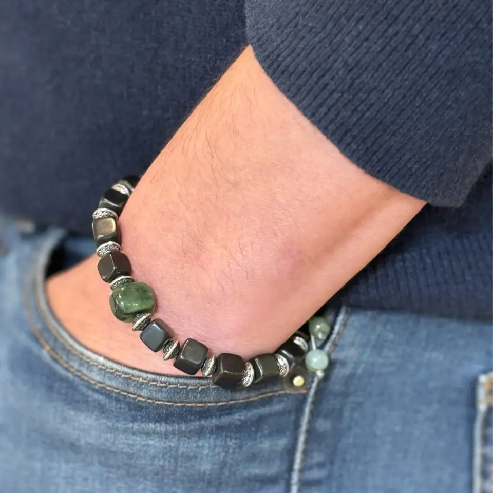 Mise en situation du bracelet homme en pierres de Shungite et de Jade, avec des intercalaires cylindriques finement gravés en argent et un système de cordon réglable.